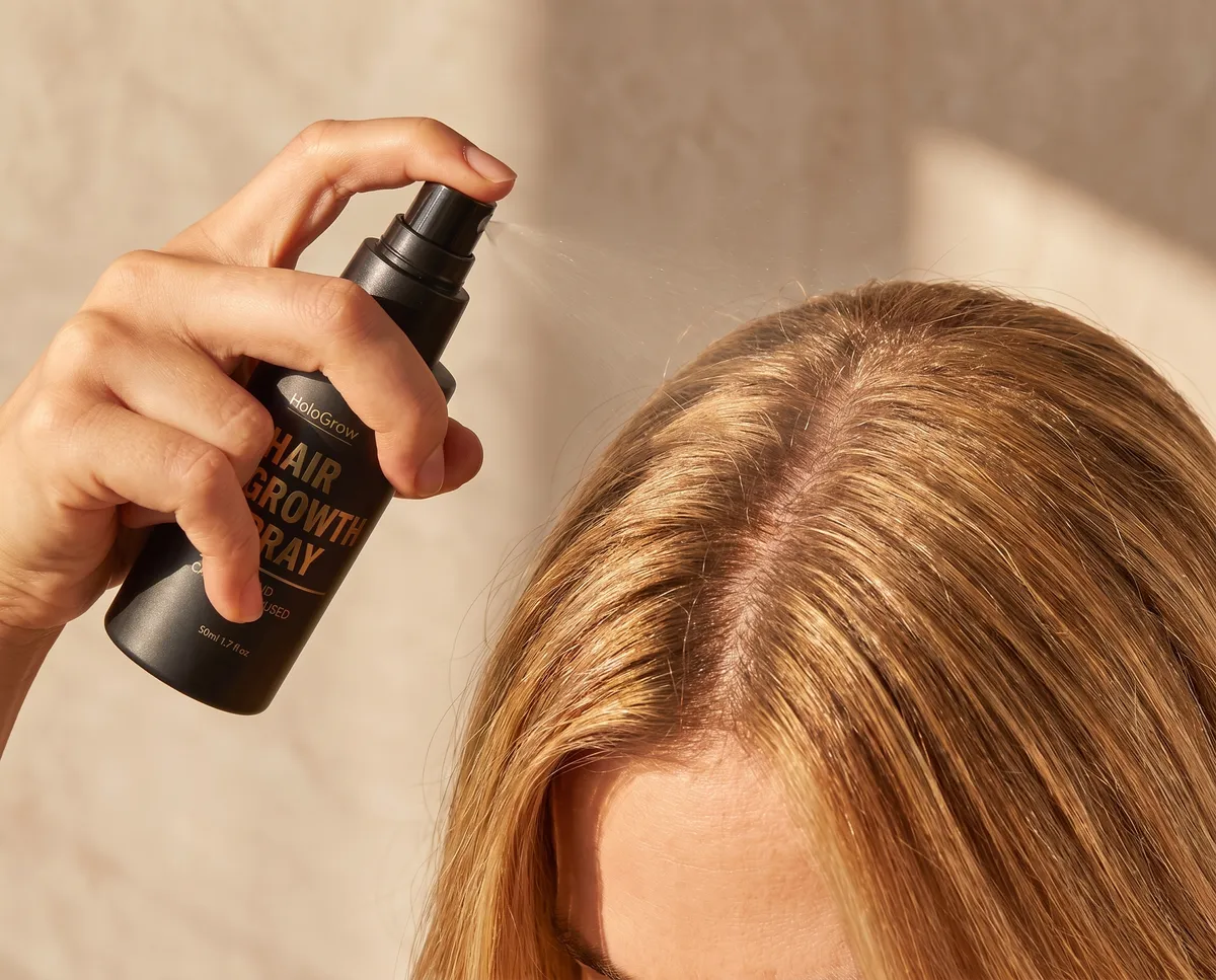 Spraying HaloGrow onto the scalp along a part