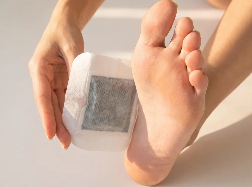 Applying a Bandoo patch to the sole of a foot